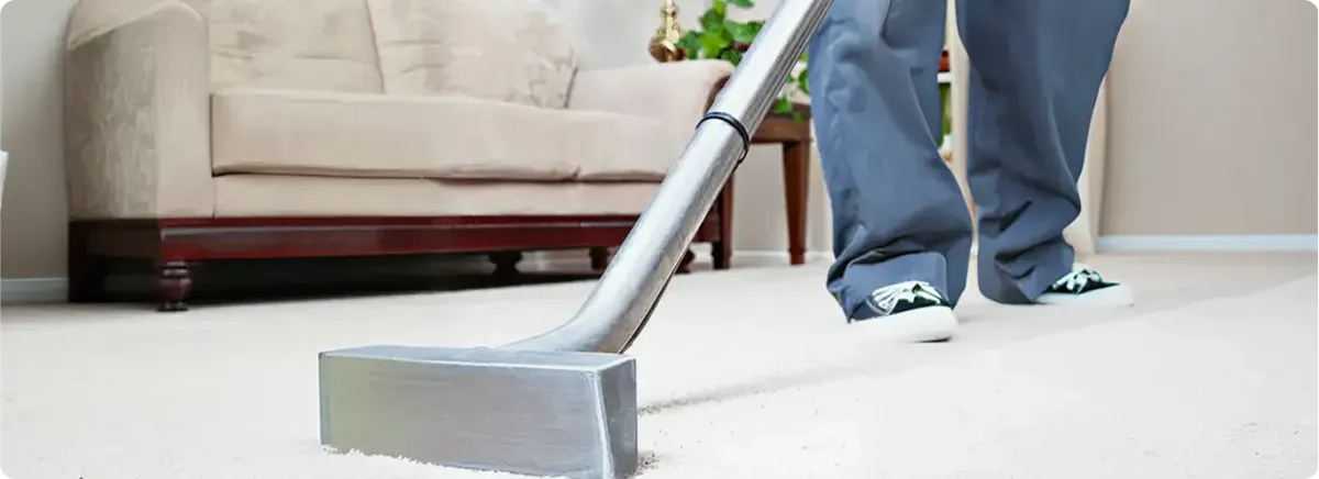 Carpet cleaning technician using a hot-water extraction wand on a light-colored carpet in a living room, Savannah, GA.